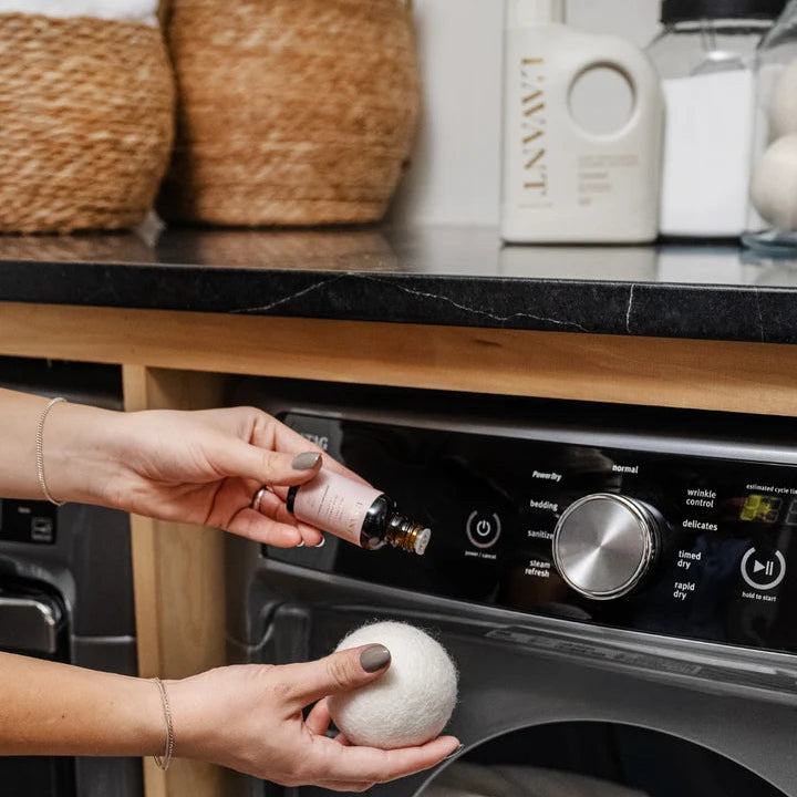 L’AVANT Collective Laundry Fragrance Oil being applied to a wool dryer ball for adding fragrance to freshly dried laundry.