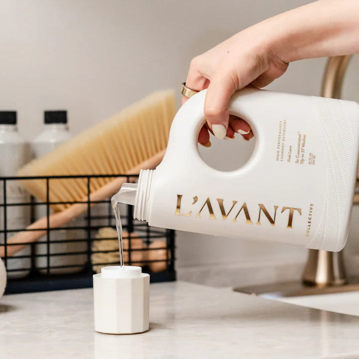 L’AVANT Collective liquid laundry detergent being poured into the measuring cap before washing