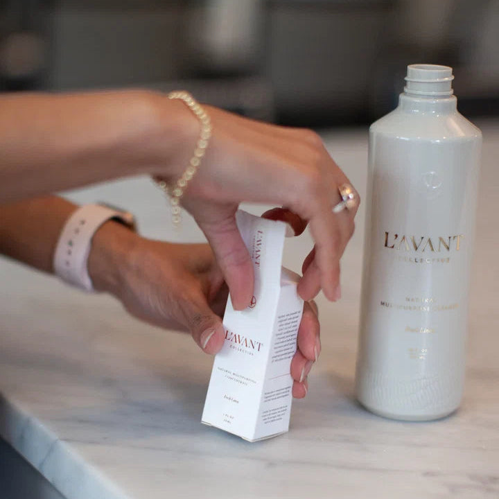L’AVANT natural multipurpose cleaner concentrate refill being removed from its box beside a reusable cleaner bottle
