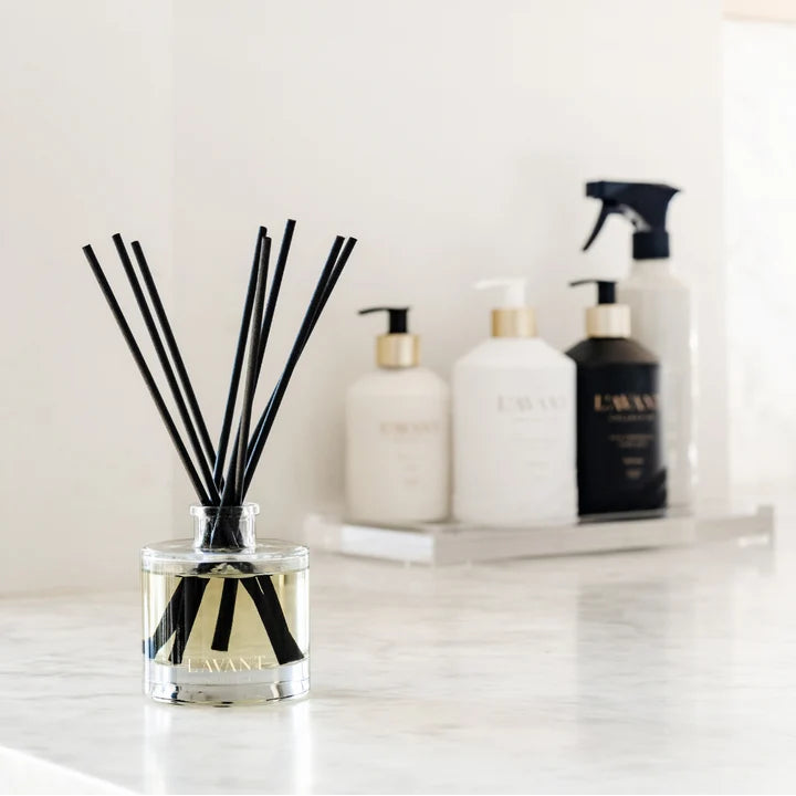 L’AVANT Collective reed diffuser with black reeds displayed on a marble countertop with coordinating home products in the background.