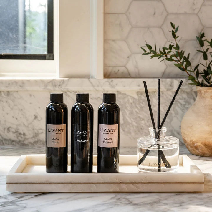L’AVANT Collective reed diffuser refill oils in Ambre Santal, Fresh Linen and Blushed Bergamot displayed with a glass reed diffuser.
