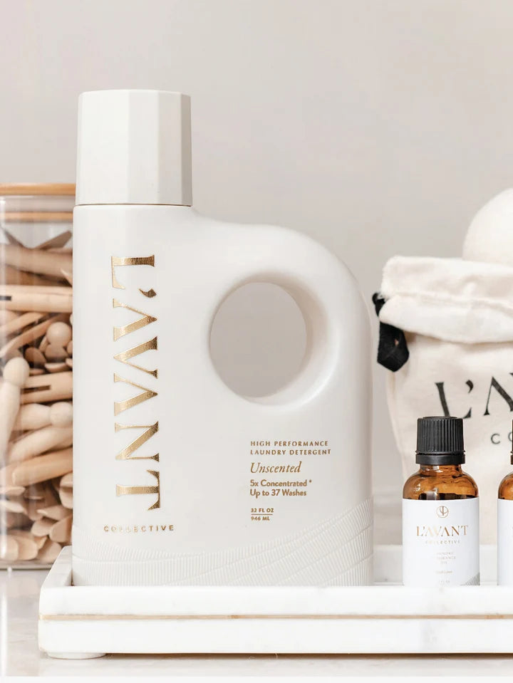 L’AVANT Collective Unscented Laundry Detergent displayed with laundry fragrance oils and laundry accessories