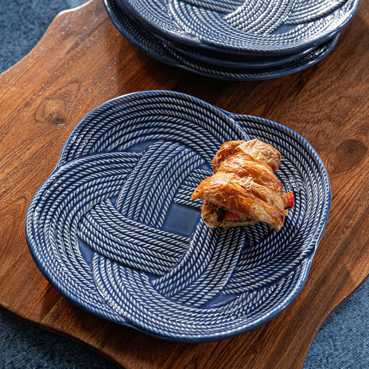 Le Panier Mystic Knot Dessert/Salad Plate in Denim styled for serving with a classic woven border and distinctive blue knot accents.