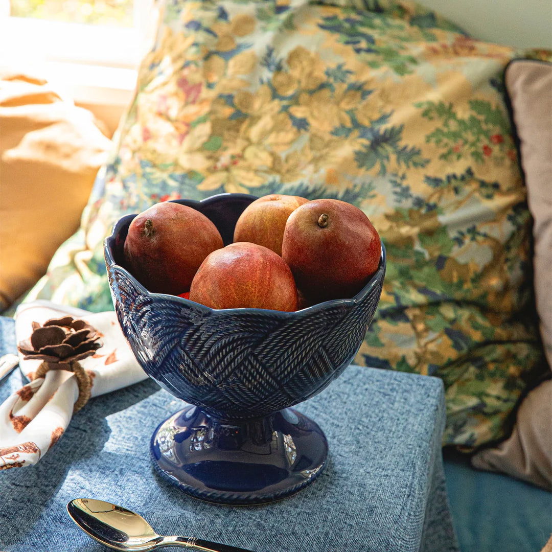 Le Panier Mystic Knot Footed Bowl in Denim styled as an elegant serving bowl with woven detailing and sculptural blue knot accents.