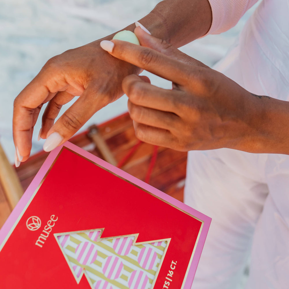 Lifestyle image of a woman using the Holiday Body Melt Set to moisturize her hand. 