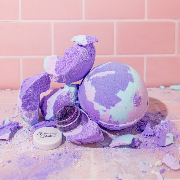 Musee Lavender Haze surprise bath balm unwrapped and places next to a broken one, surprise body/hair glitter revealed. 
