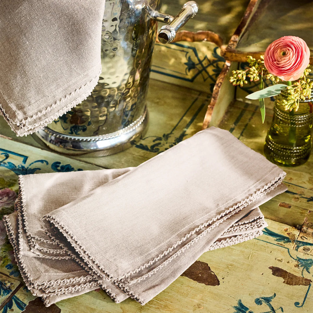 Stack of natural linen napkins with crochet trim styled on a decorative table for elegant entertaining