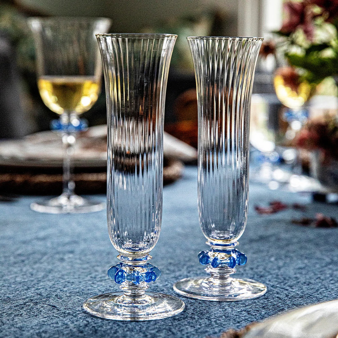 Pair of Nell Ruffle Flutes in Chambray displayed on an elegant table setting with ribbed glass and blue ruffle accents.
