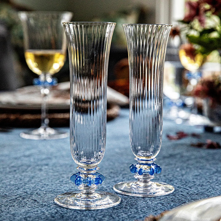 Pair of Nell Ruffle Flutes in Chambray displayed on an elegant table setting with ribbed glass and blue ruffle accents.