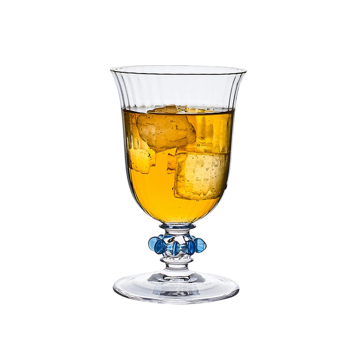 Nell Ruffle Goblet in Chambray filled with a beverage, showcasing a ribbed clear glass bowl and signature blue ruffle stem detail.