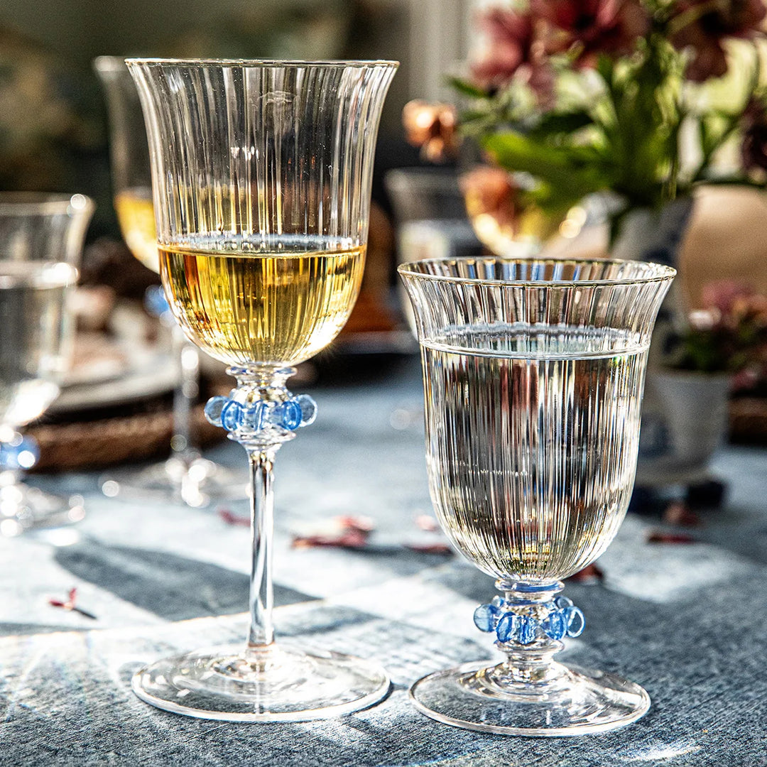 Nell Ruffle Goblet in Chambray styled on an elegant table setting with clear ribbed glass and decorative blue ruffle accents.