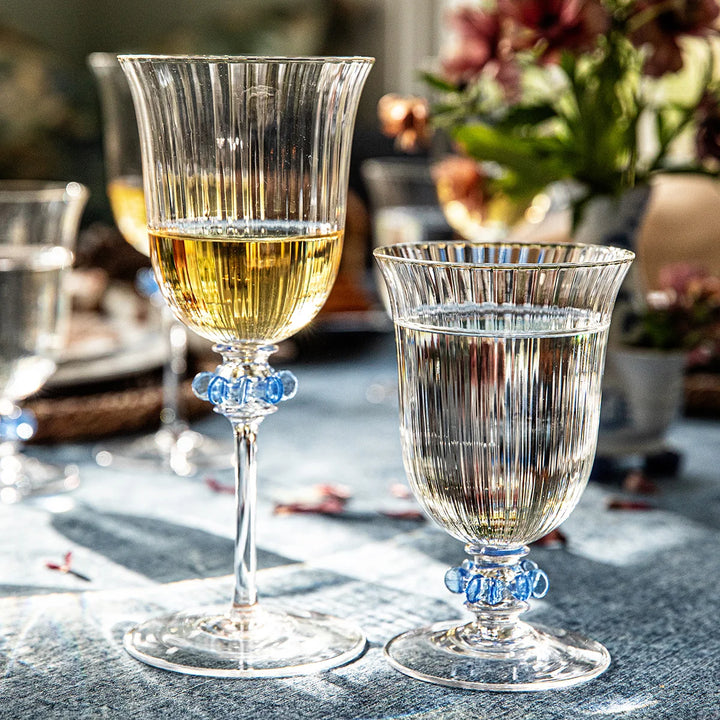Nell Ruffle Goblet in Chambray styled on an elegant table setting with clear ribbed glass and decorative blue ruffle accents.