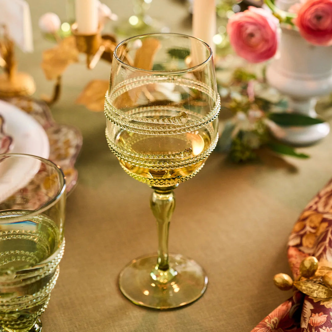 Olive green stemmed wine glass with raised textured bands filled with white wine on an elegant floral tablescape