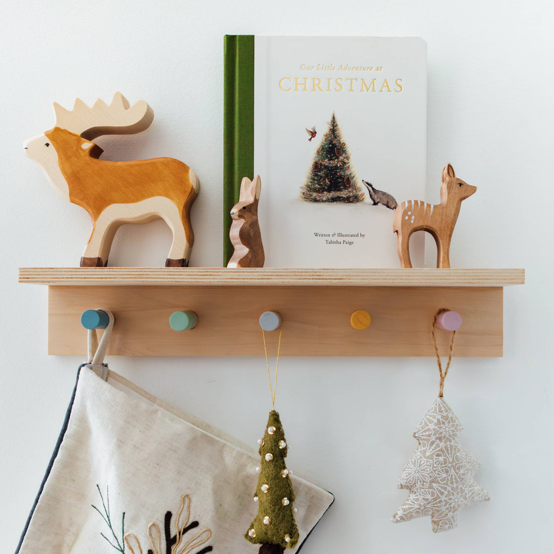 Our Little Adventure at Christmas book displayed with wooden woodland animals and hanging Christmas decorations