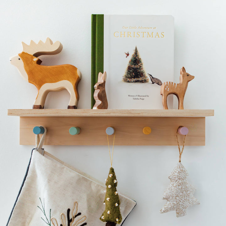 Our Little Adventure at Christmas book displayed with wooden woodland animals and hanging Christmas decorations