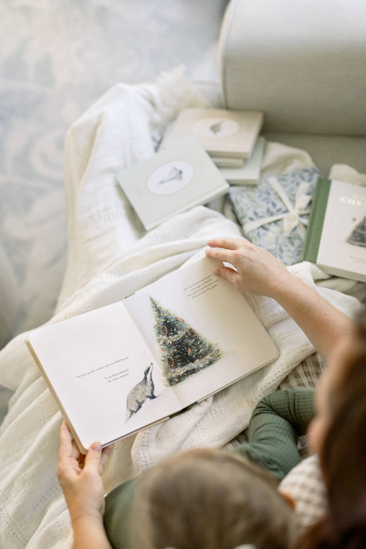 Family reading Our Little Adventure at Christmas with watercolor Badger and Christmas tree illustrations visible