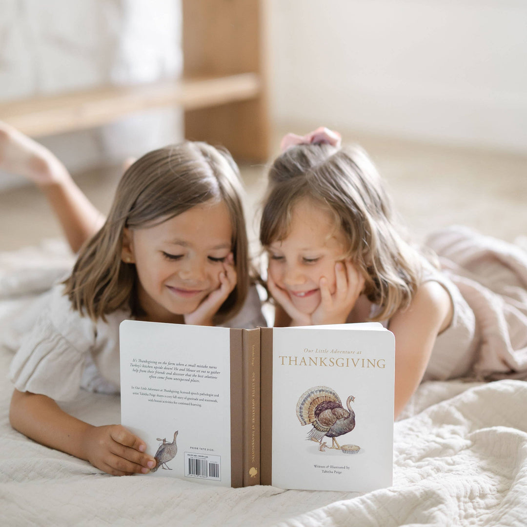 Two young children reading Our Little Adventure at Thanksgiving together