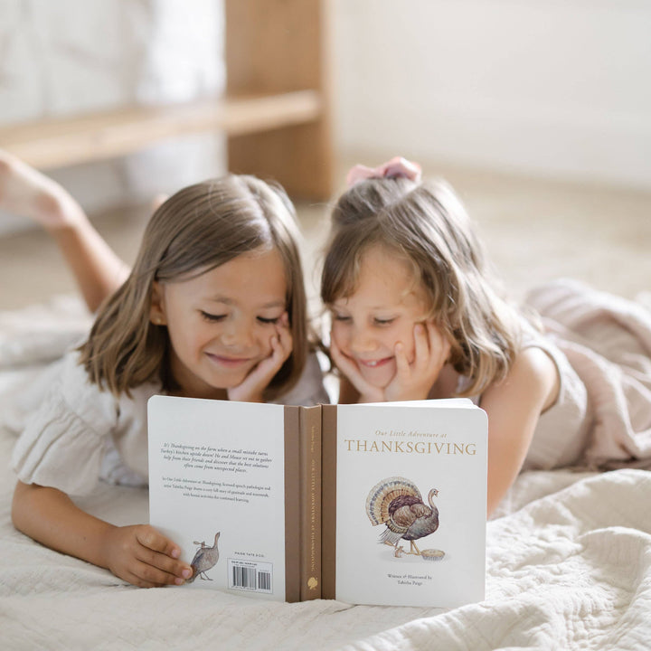 Two young children reading Our Little Adventure at Thanksgiving together