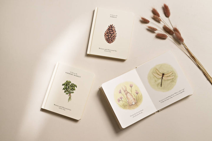 Our Little Adventures board books with an open forest story spread featuring watercolor rabbit and dragonfly illustrations