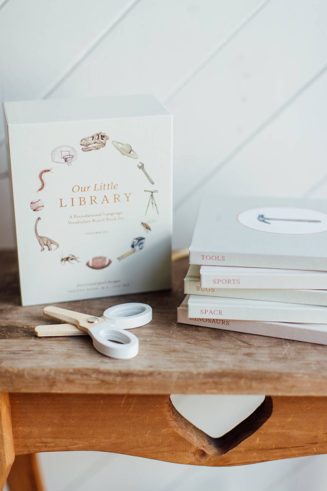 Our Little Library Vol. 3 slipcase beside stacked board books for Tools, Sports, Bugs, Space, and Dinosaurs