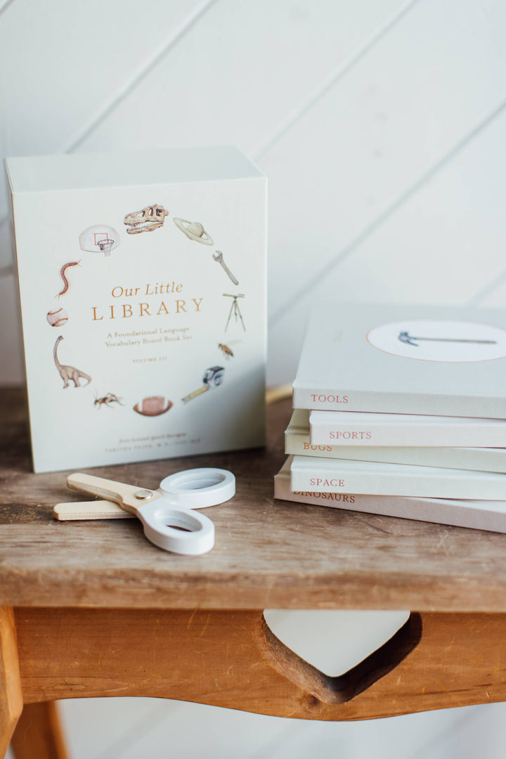 Our Little Library Vol. 3 slipcase beside stacked board books for Tools, Sports, Bugs, Space, and Dinosaurs