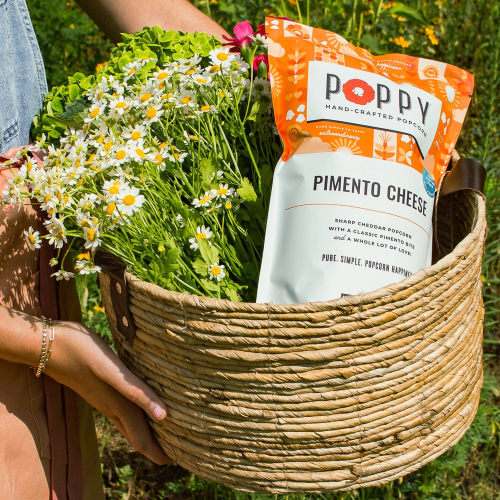 Poppy Pimento Cheese Hand-Crafted Popcorn displayed in a woven basket with fresh flowers