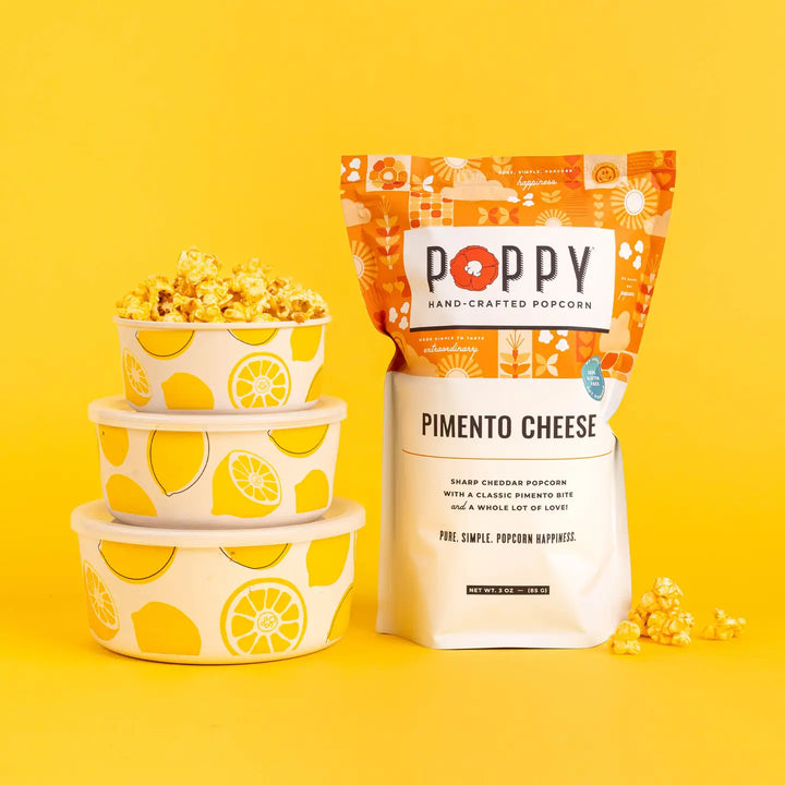 Poppy Pimento Cheese Hand-Crafted Popcorn displayed with bowls of popcorn on a bright yellow background