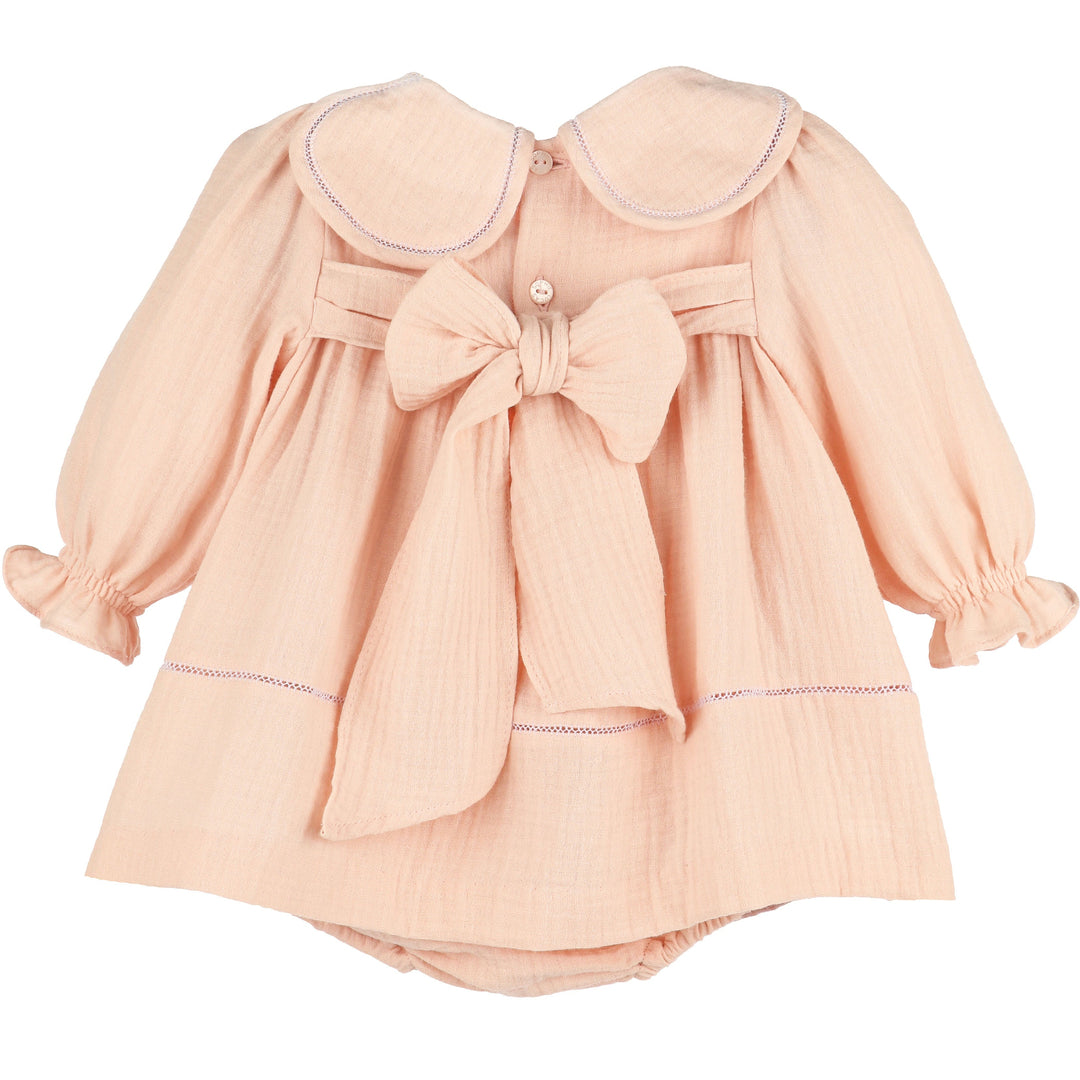 Back view of Pink Cuddle Cotton Petal Float featuring a petal collar, long ruffled sleeves, button closure, and oversized statement bow.