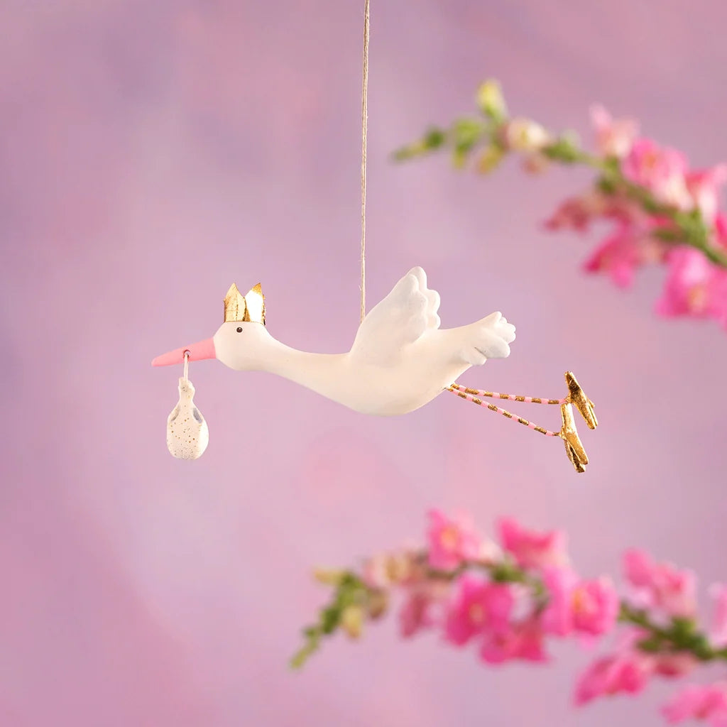 Pink Flying Stork Ornament featuring a white stork with gold accents, pink beak, and tiny baby bundle, perfect for baby girl gifts and Christmas decor.