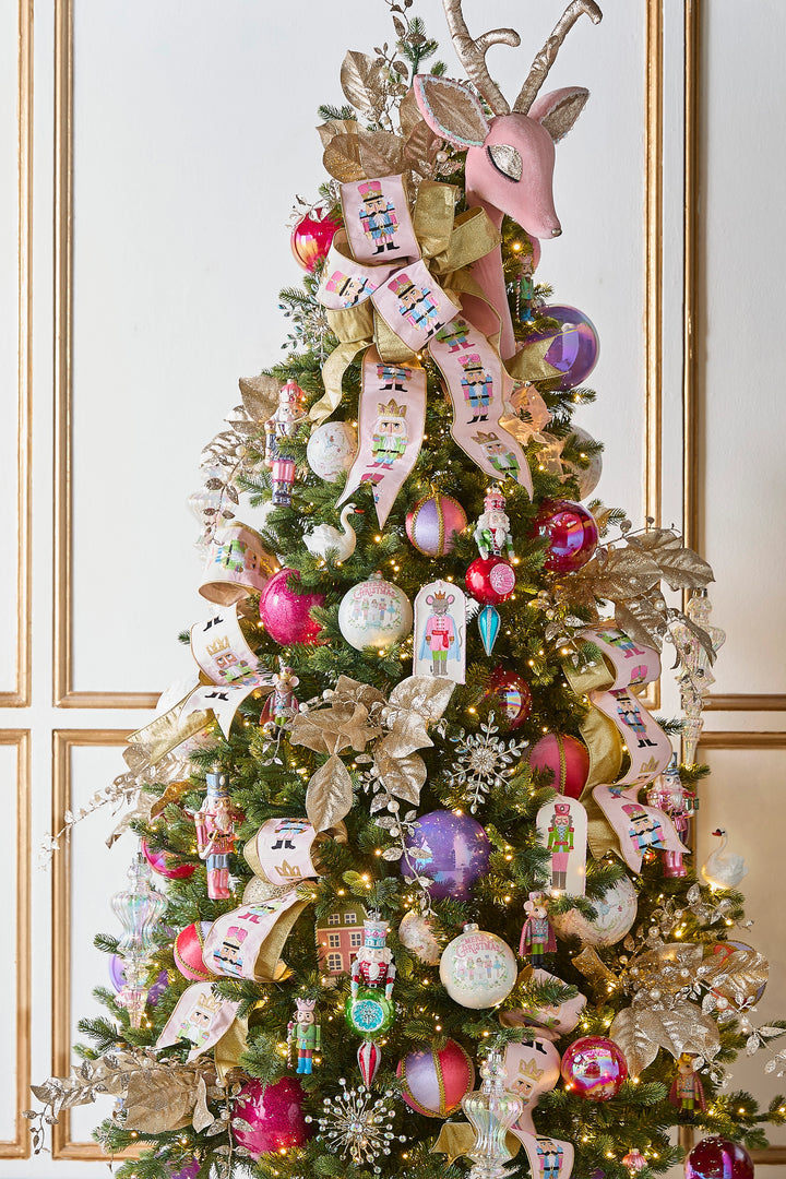 Pink embroidered nutcracker wired ribbon cascading through an elegant Christmas tree decorated with colorful nutcracker ornaments, pink and purple baubles, metallic gold ribbon, gold poinsettias and a whimsical pink reindeer topper.