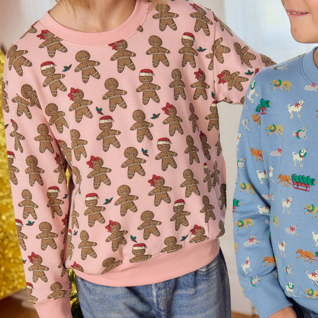 Close-up of girl wearing pink Gingerbread Cookie Play Sweatshirt with festive Santa hat and bow print