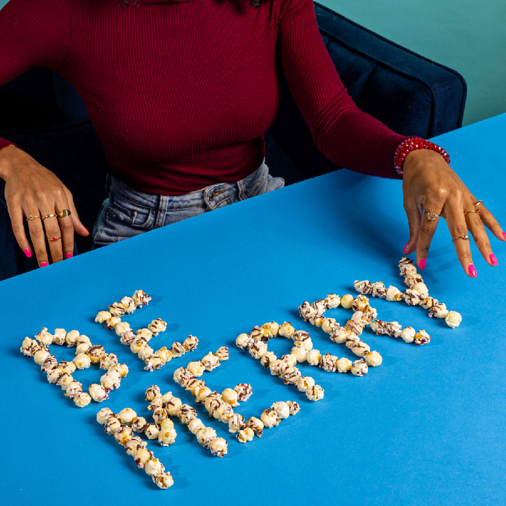 Chocolate peppermint popcorn arranged in festive lettering on a blue tabletop