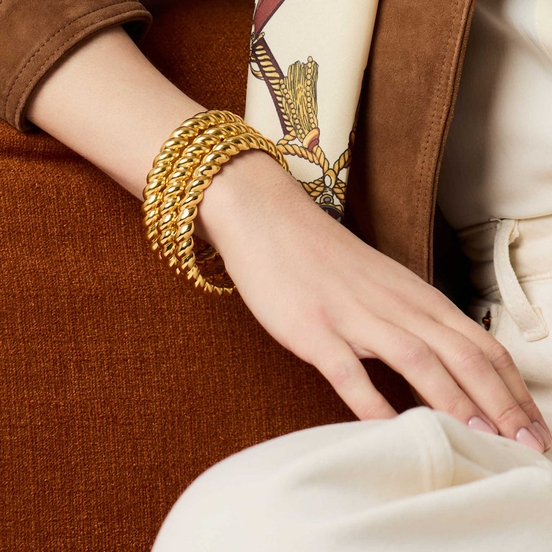 Model wearing stacked gold Ravello Bangle bracelets