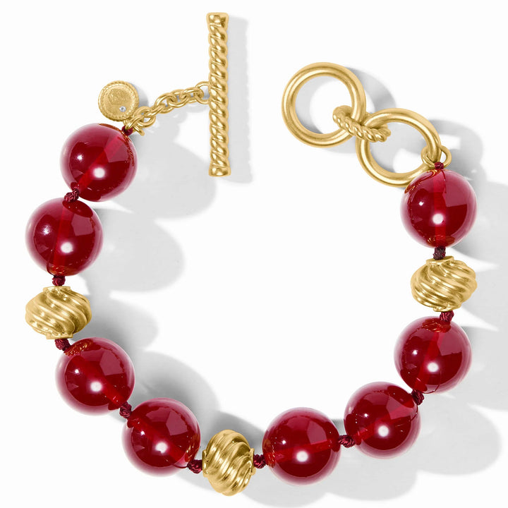 Close-up view of Ravello Bracelet in cranberry with round cabochons, gold accents, and decorative toggle closure