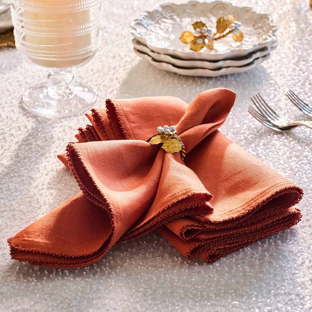 Rust linen napkins styled with a gold leaf and silver berry napkin ring for an elegant fall table setting
