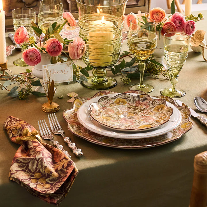 Sage green linen tablecloth styled with floral dinnerware, pink flowers, green glassware and candles for an elegant fall tablescape