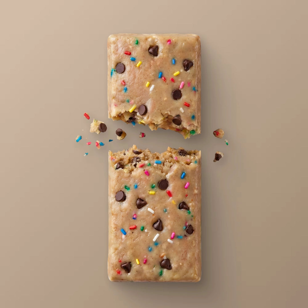 Close-up of Stars + Honey Cake &amp; Ice Cream collagen protein bar texture with chocolate pieces and rainbow sprinkles