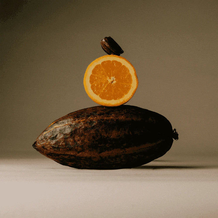 Cacao pod with fresh orange slice representing The Conscious Bar Orange Blossom dark chocolate