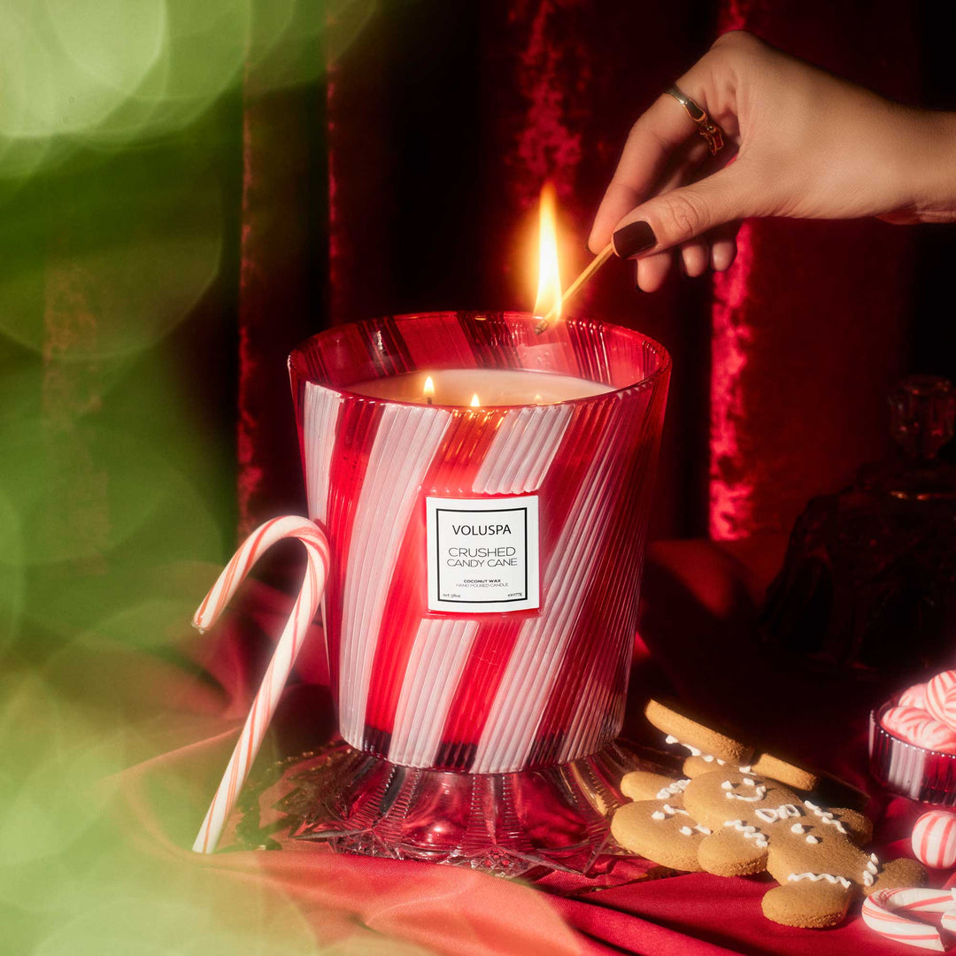 Lit Voluspa Crushed Candy Cane 3 Wick Hearth Candle styled with candy cane and gingerbread Christmas décor