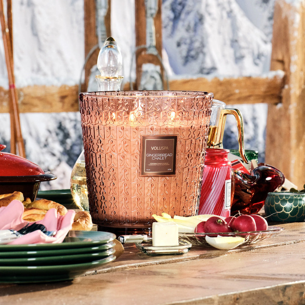 Lit Voluspa Gingerbread Chalet 5 Wick Hearth Candle styled on a festive holiday dining table