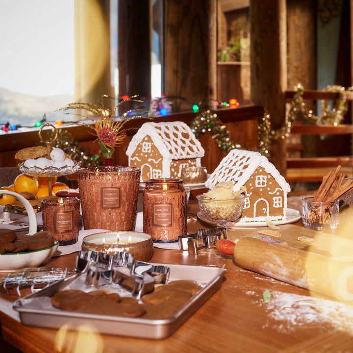 Voluspa Gingerbread Chalet Mini Tin Candle displayed with coordinating holiday candles and gingerbread houses