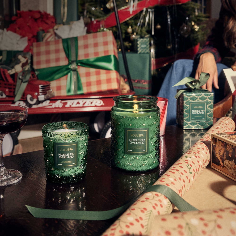 Voluspa Noble Fir Garland Classic Candle displayed in a festive Christmas gift wrapping scene