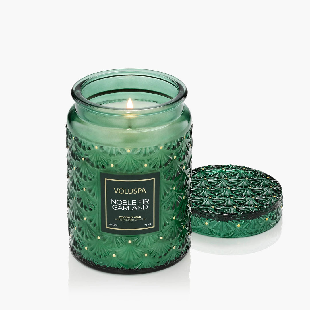 Lit Voluspa Noble Fir Garland Large Jar Candle in embossed green glass with decorative matching lid