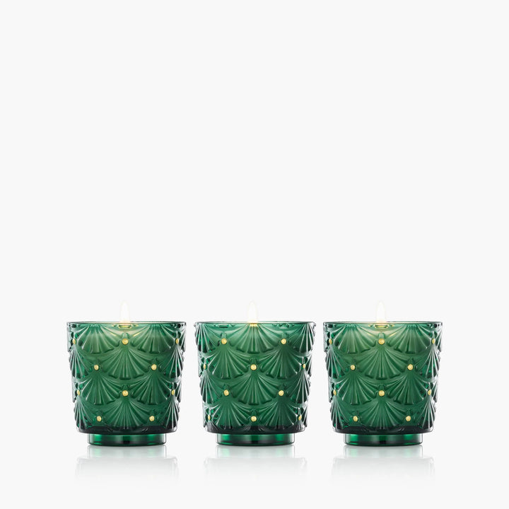 Three Voluspa Noble Fir Garland Mini Pedestal candles in embossed emerald green glass vessels with gold accents
