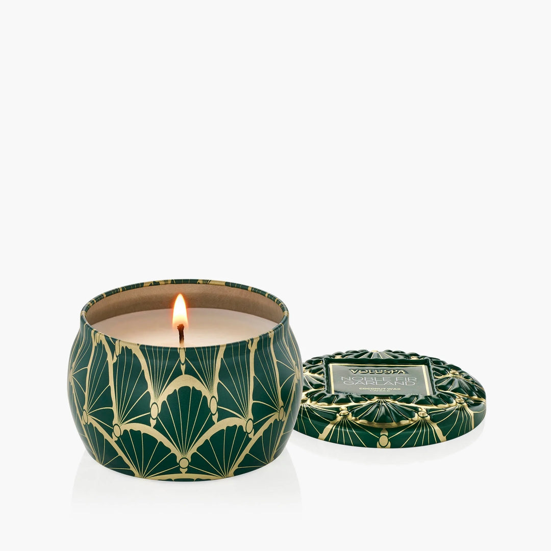 Lit Voluspa Noble Fir Garland Mini Tin Candle with coordinating emerald green and gold decorative lid