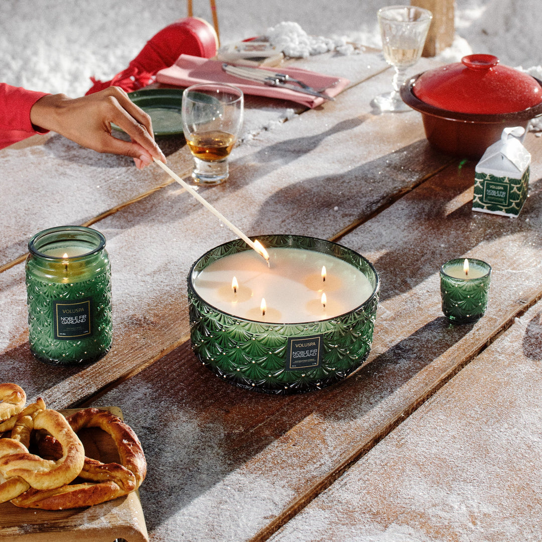 Voluspa Noble Fir Garland candles including Ornament Pedestal Candle styled on a festive winter holiday table
