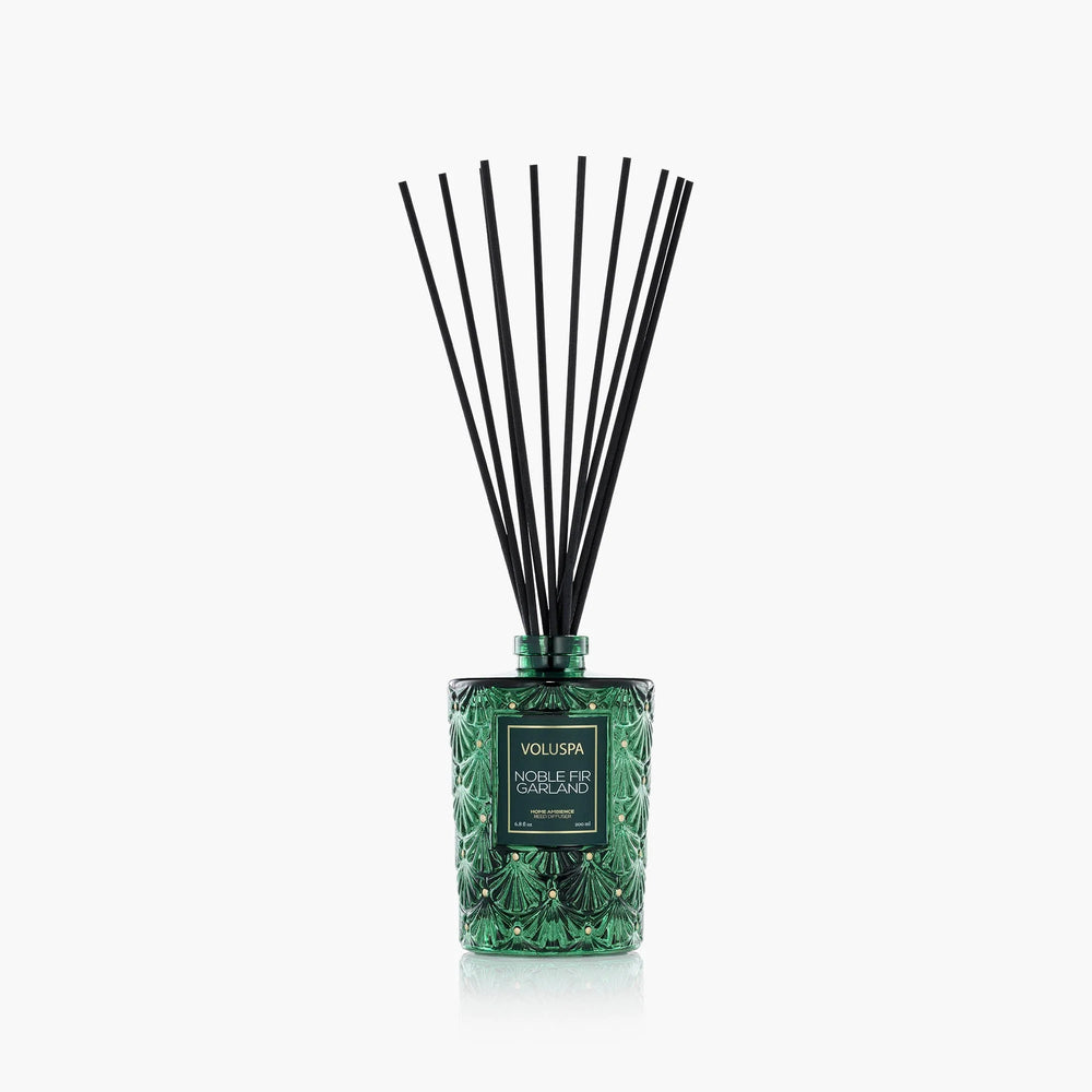 Voluspa Noble Fir Garland Reed Diffuser in decorative green glass vessel with black fragrance reeds