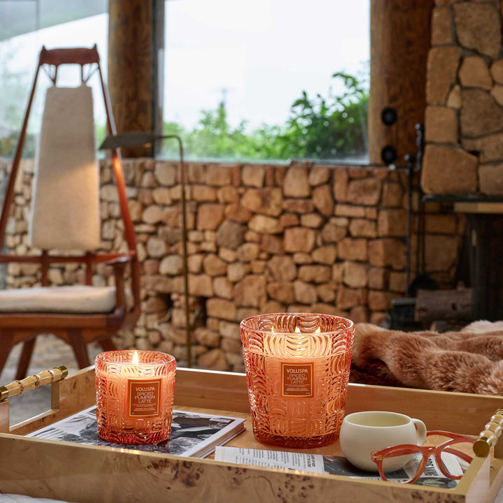 Voluspa Spiced Pumpkin Latte candles glowing on a tray in a cozy stone interior