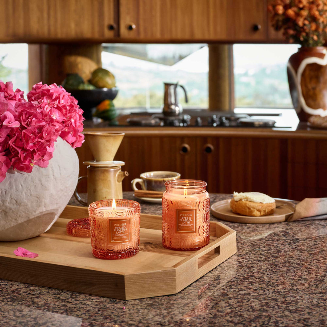 Voluspa Spiced Pumpkin Latte candles displayed on a wooden tray in a cozy kitchen