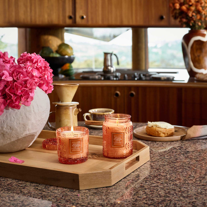 Voluspa Spiced Pumpkin Latte candles displayed on a wooden tray in a cozy kitchen